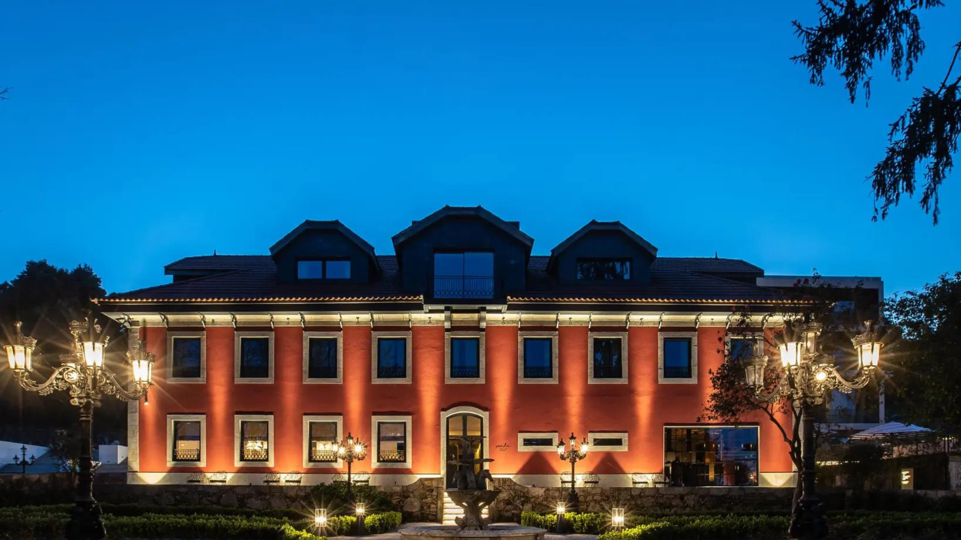 Exterior view of the Vinha Boutique Hotel, showcasing its grand 16th-century architecture surrounded by three hectares of meticulously tended gardens