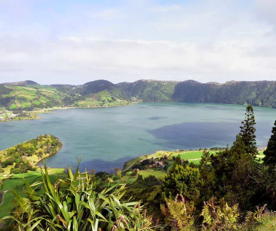 Breathtaking vista of Sete Cidades, Azores. The image captures the stunning twin lakes within a volcanic crater, surrounded by lush greenery and dramatic cliffs. One lake shines in vibrant blue hues, while the other displays serene green tones, creating a striking contrast that reflects the natural beauty of this iconic destination.