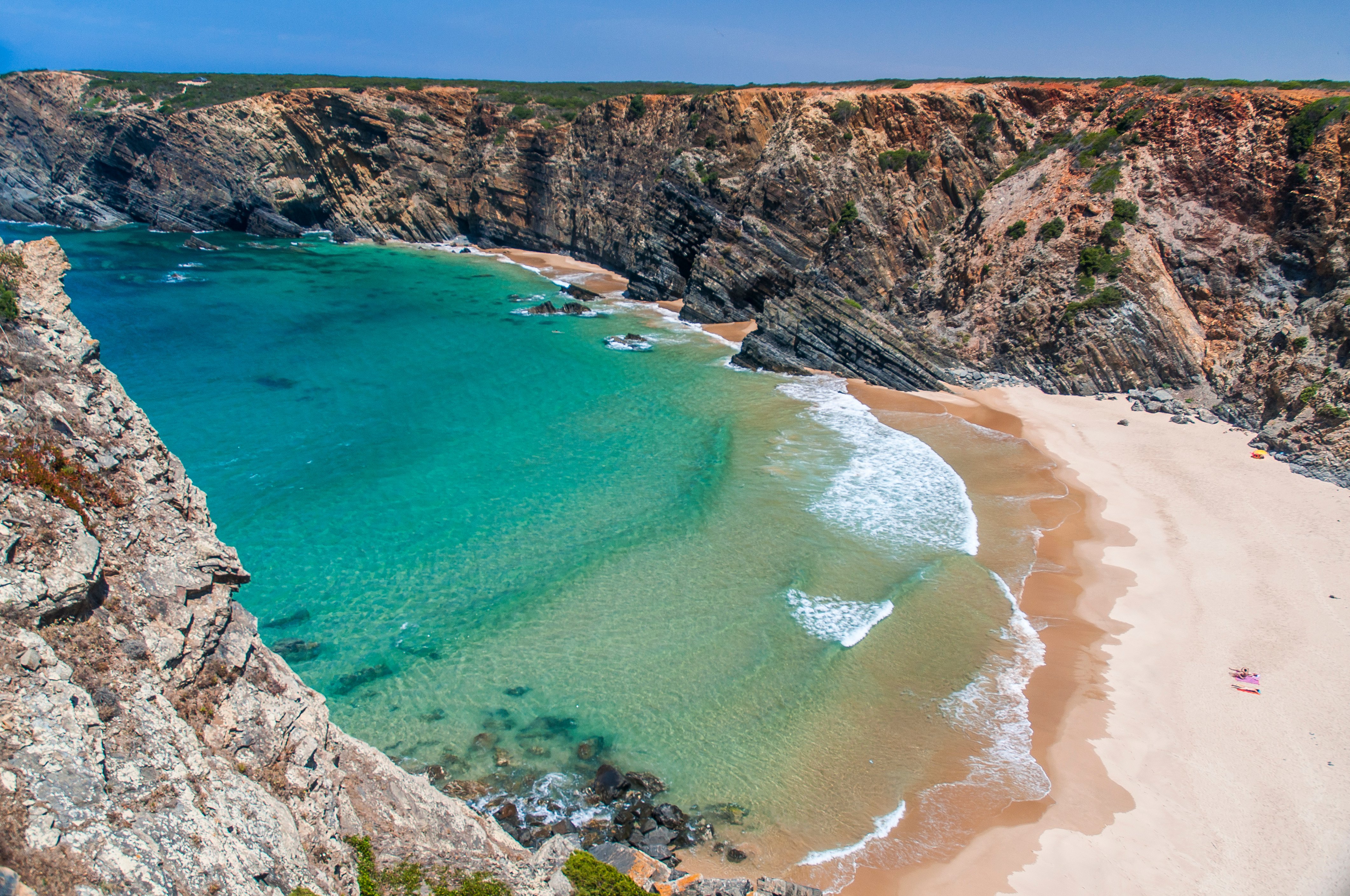 Aerial Landscape Photo Of A Large, Nearly Empty Beach With Big, Steep Cliffs On Each Side At The