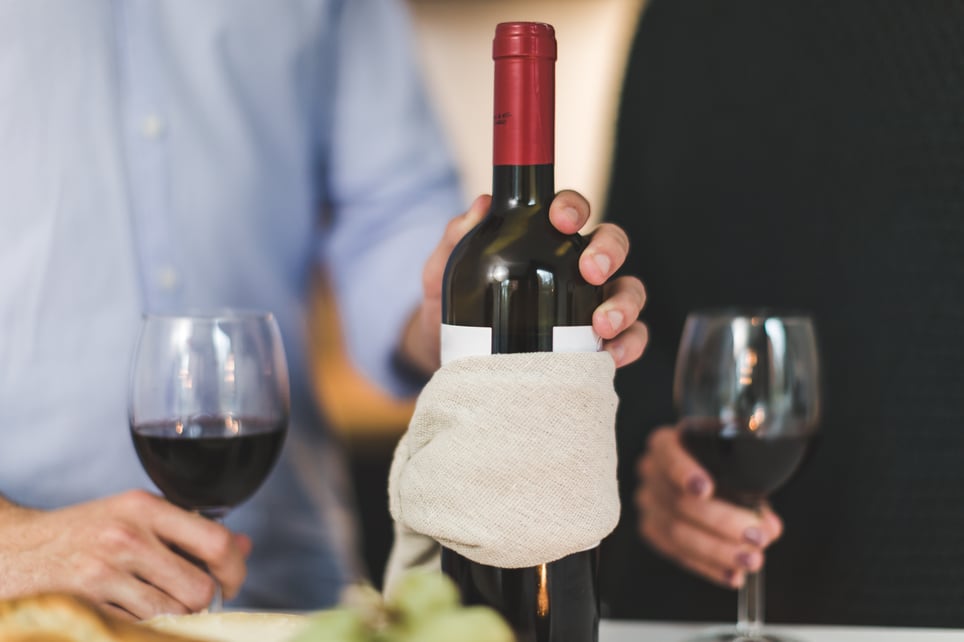 man-holding-white-labeled-red-wine-bottle-near-wine-glasses-374877