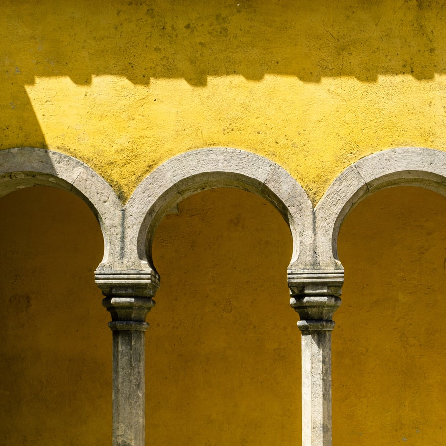 Exterior view of Sintra Palace (Palácio Nacional de Sintra) in Portugal, characterized by its distinctive blend of architectural styles, including Gothic, Moorish, and Manueline influences, set against a backdrop of lush greenery.